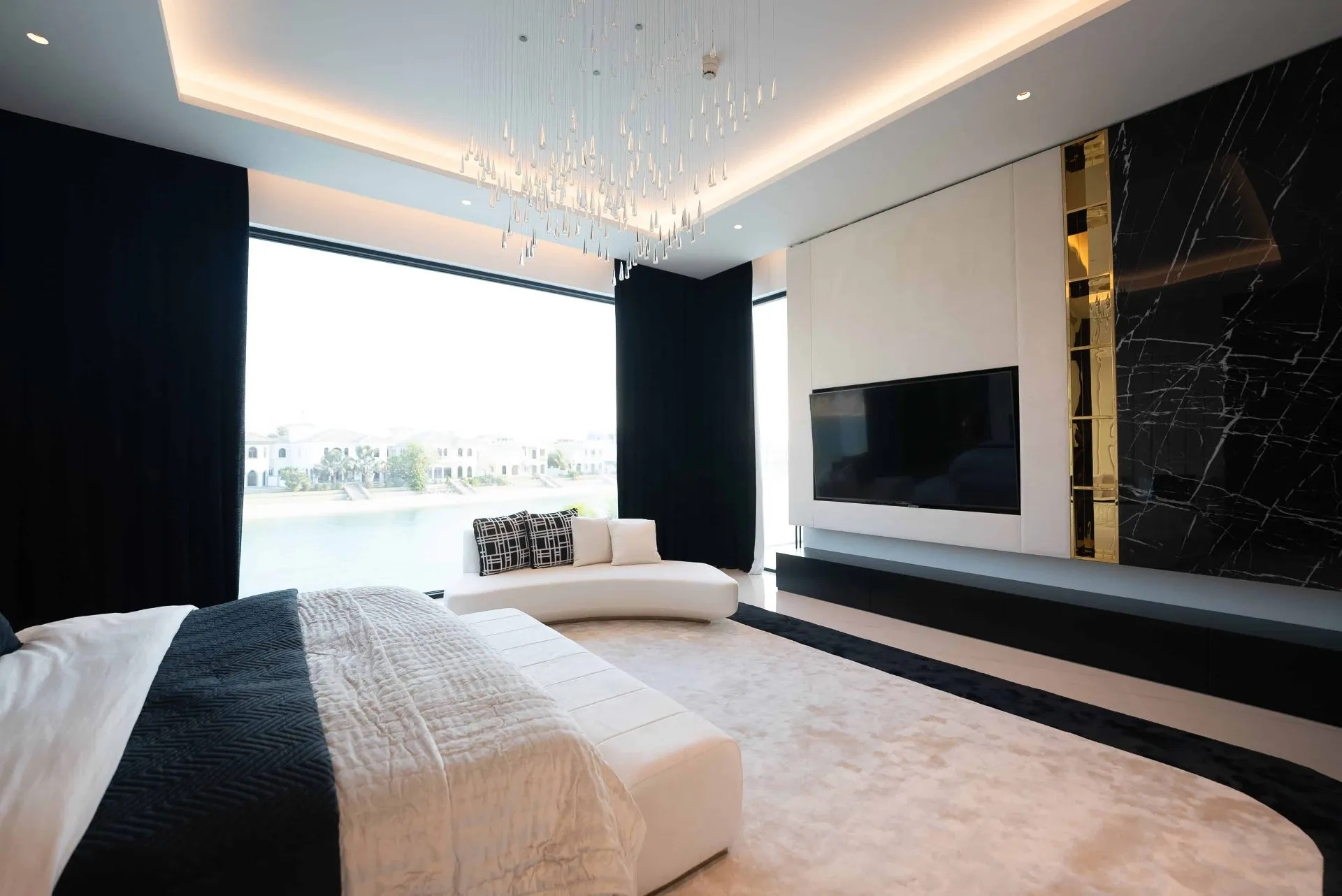 A stylish bedroom with a big TV and a sleek black and white theme.