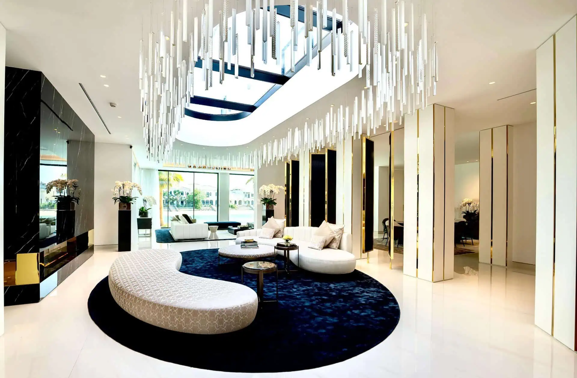 a  room with a large chandelier , a white couch and black rug 