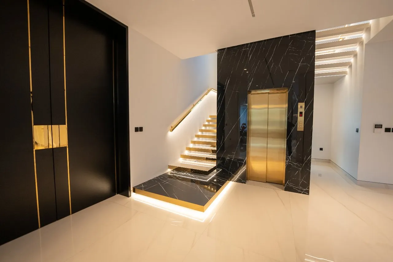 A sleek elevator with gold accents and black marble, adding a touch of luxury to the modern design