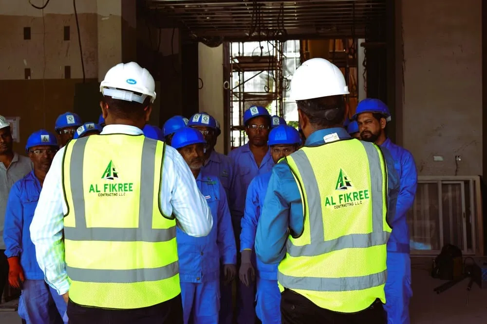 Engineer wearing Al fikree jacket giving instruction to labours on a construction site.