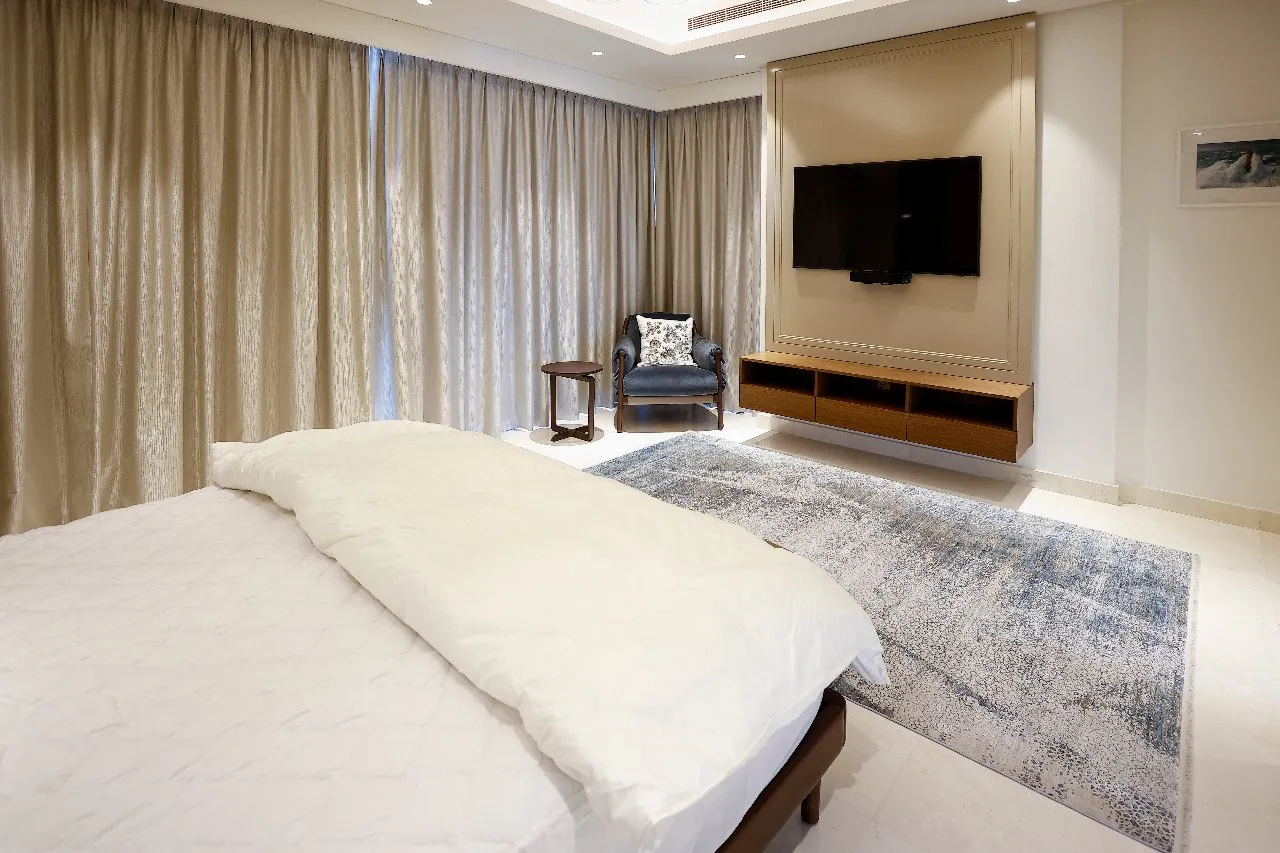 A cozy bedroom with a spacious bed and a sleek flat screen TV.