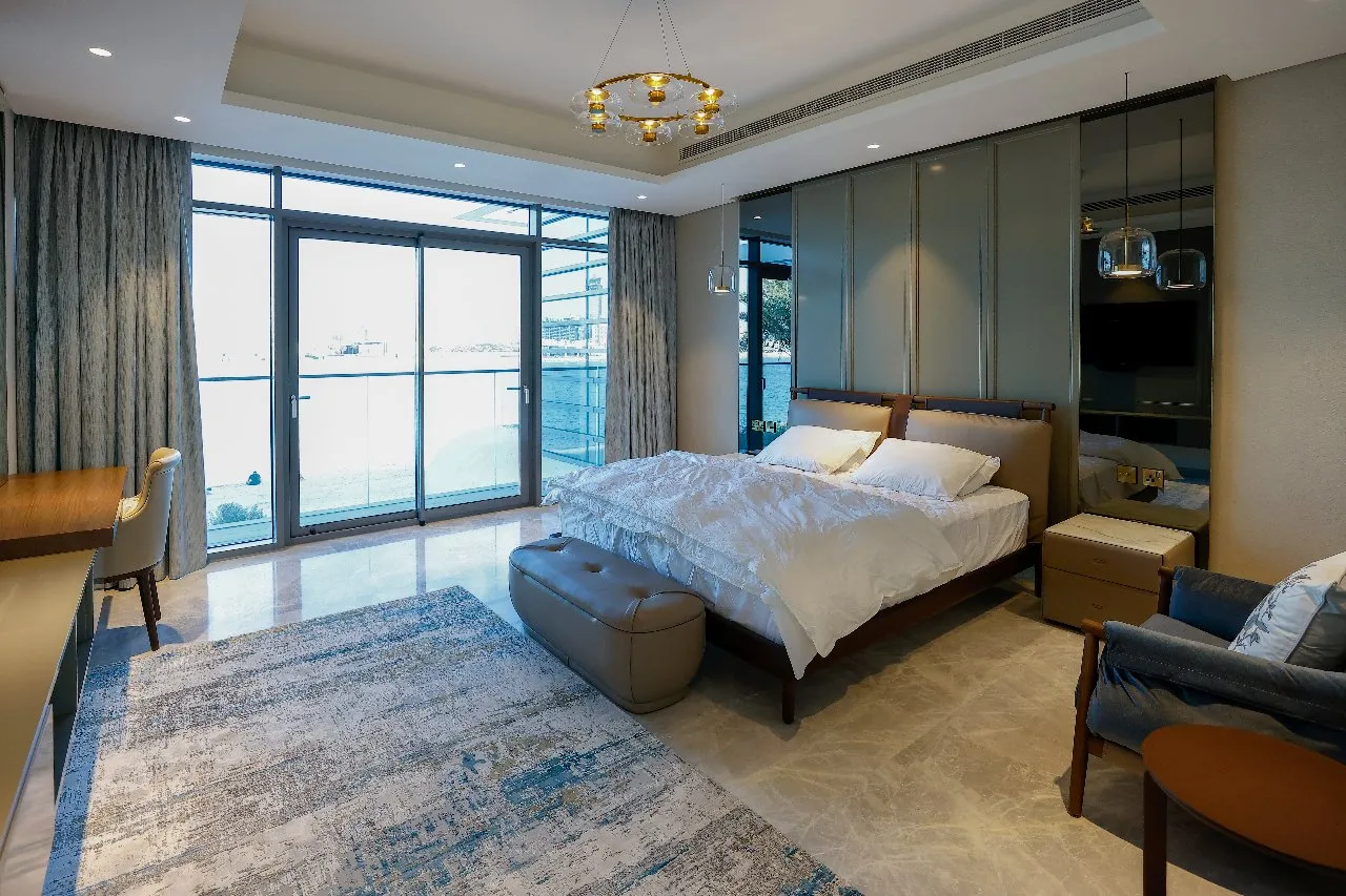  A cozy bedroom with a spacious bed and a glass door, offering a serene view of the surroundings.